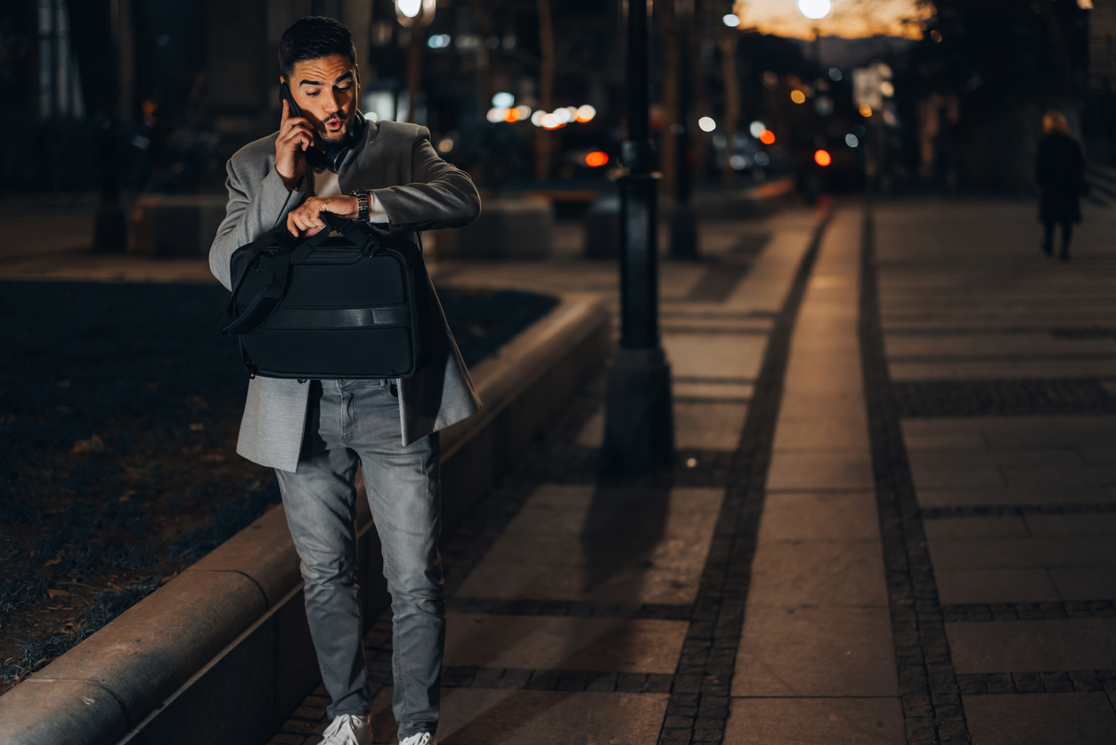 Person a mobile phone with briefcase looking at watch in street